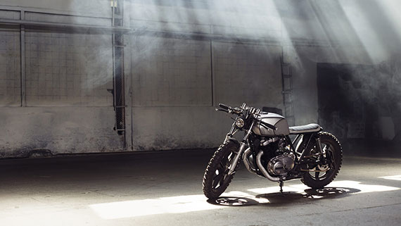 A parked motorcyle on serene highway and open fields