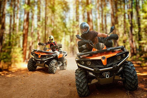 Two ATV riding a trail in the woods